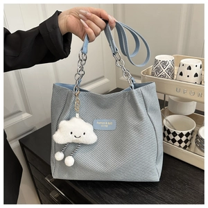 Detail of light blue textured tote bag with cloud charm and chain leather shoulder strap