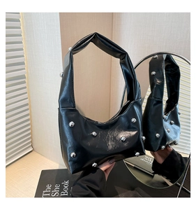 Detail shot of black patent leather handbag with silver sphere rivets and sleek glossy finish