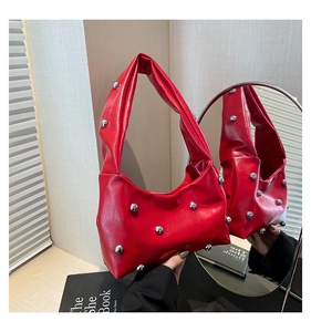Detailed shot of vibrant red handbag featuring polished silver studs and smooth finish