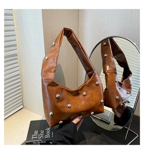 Detail view of caramel brown hobo bag with silver rivets and smooth glossy texture