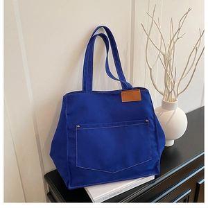 Close-up of klein blue canvas tote bag showing contrast stitching and brown leather tag