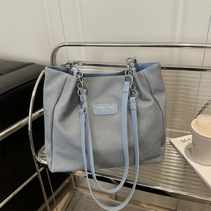 Light blue woven tote bag with silver chain straps and leather logo tag for women