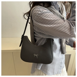 Close-up of dark grey woven texture shoulder bag featuring a silver bow logo detail