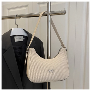 Close-up of beige woven hobo bag featuring a silver metal bow accent and zipper