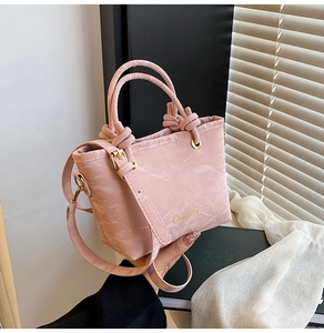 Detail of pink marble pattern handbag with golden FASHION logo and knotted handles