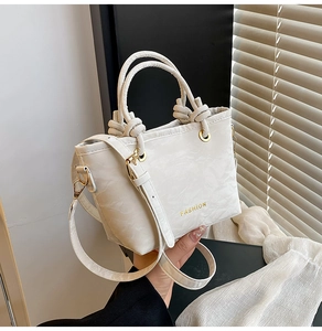 Detail view of cream white bucket bag with knot handles and FASHION lettering