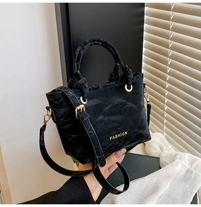 Detail of black velvet texture fashion handbag with golden lettering and gold hardware