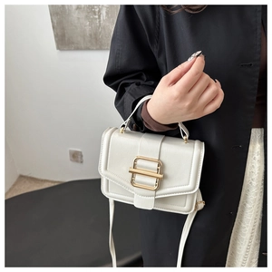 Detail of white leather crossbody bag with golden square buckle on a model wearing black
