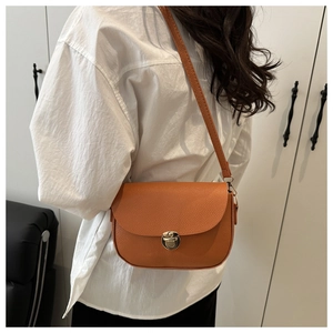 Close-up of brown litchi pattern leather saddle bag with a golden round metal clasp detail