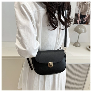 Close-up of black litchi pattern leather shoulder bag with golden round metal lock