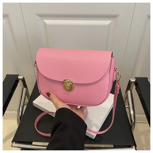 Detailed view of pink lychee grain leather handbag with gold metal lock and shoulder strap