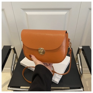 Detail of orange saddle bag showing lychee grain texture and gold metal buckle