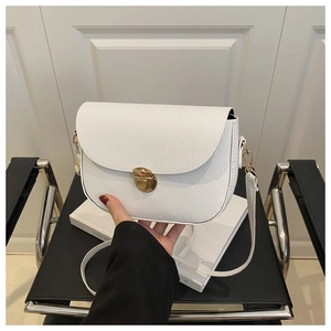Close-up of white lychee pattern saddle bag featuring a gold circular twist lock