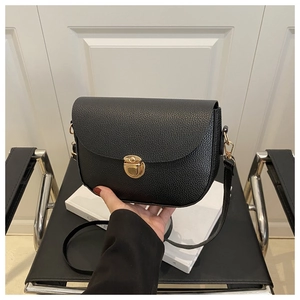 Close-up of black lychee grain texture with elegant gold hardware on a crossbody bag