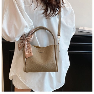 Close-up of khaki bucket bag with lychee texture, silk scarf, and detachable strap