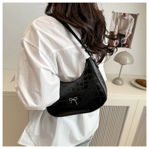Detail der schwarzen Hobo-Bag mit Krokodilprägung und silbernem Schleifen-Accessoire