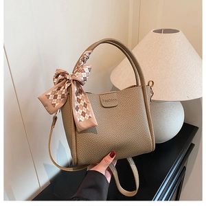 Detail of khaki bucket bag with lychee texture and decorative plaid silk scarf handle