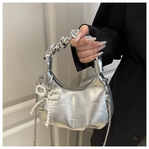 Detail showing metallic silver hobo bag with pleated handle and pearl bow pendant