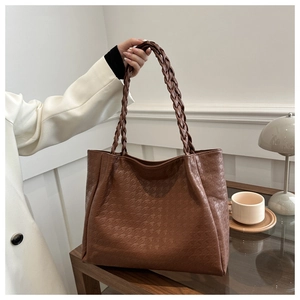 Détail d'un cabas marron avec texture pied-de-poule et poignée tissée épaisse