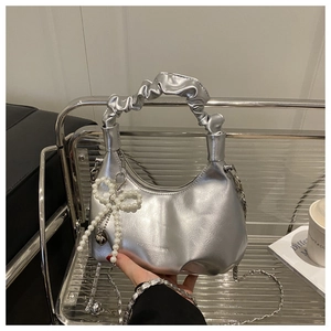 Close-up of silver pleated handbag featuring a pearl bow charm and chic chain strap