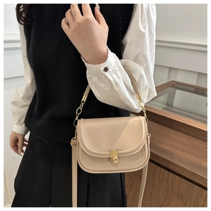 Detail of minimalist beige leather crossbody bag with elegant gold metal lock clasp
