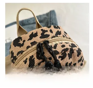 Close-up of a leopard print corduroy backpack featuring a smooth zipper and khaki handle