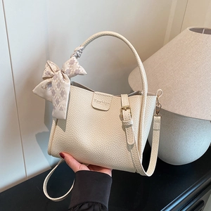 Chic beige bucket bag with lychee grain texture and elegant ribbon scarf on handle