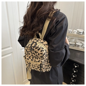 Rear view of a mini leopard print corduroy backpack on a model in a cozy home setting