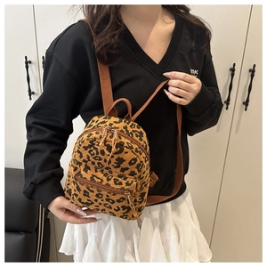 Detailed close-up of leopard print corduroy texture and front zipper pocket on backpack