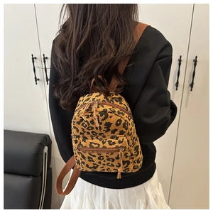 Back view of a model wearing a mini leopard print corduroy backpack with brown straps