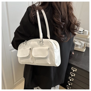 Detailed view of white glossy underarm bag featuring dual front pockets and sleek straps