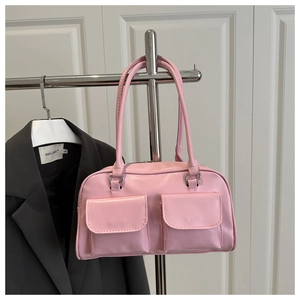 Detail of pink faux leather handbag showing front flap pockets and silver hardware
