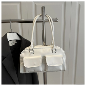 Detail view of white faux leather shoulder bag featuring silver rings and dual front pockets