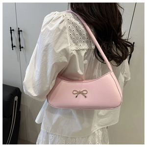Detail of pink hobo bag with golden bow buckle worn by a model in white lace top