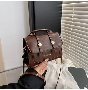 Detailed macro of vintage brown leather handbag with gold buckle and adjustable strap