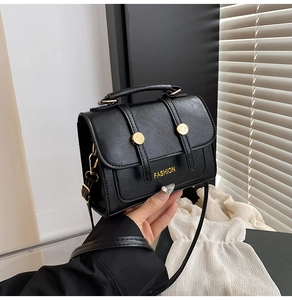 Detail of black lychee grain crossbody bag with gold FASHION buckle and adjustable strap