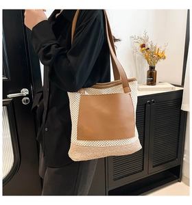 Detail of a woven beach tote bag featuring white mesh, brown faux leather pocket and straw base