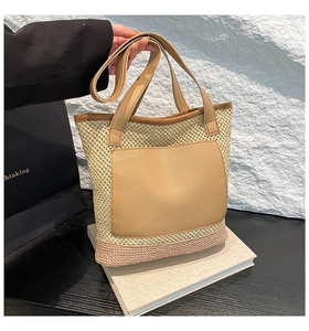 Detail of hand-woven straw tote bag with brown leather pocket and leather handle