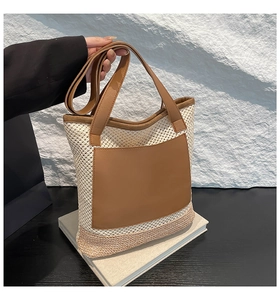 Detail of handwoven tote bag featuring a brown leather front pocket and long handles
