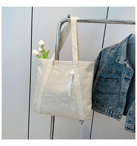 Détails du tissage d'un sac cabas en paille crème avec un élégant gland blanc décoratif