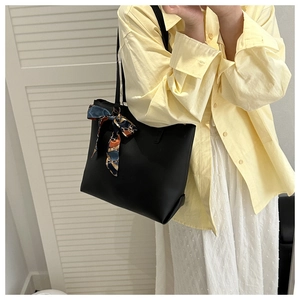 Détail d'un grand sac cabas noir minimaliste avec foulard en soie et fine bandoulière