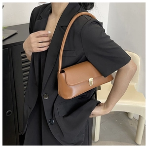 Brown vintage leather baguette bag with gold lock buckle shown on model shoulder