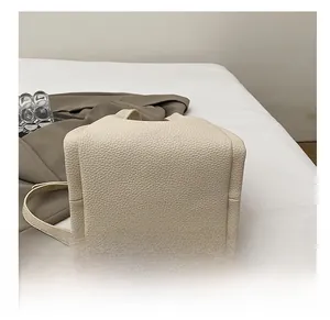 Close-up of durable base and lychee grain leather texture on beige commuter tote bag