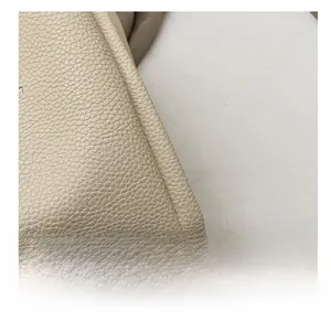 Close-up of beige lychee texture leather with precision stitching on a tote bag