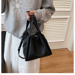 Close-up of black lychee grain leather tote bag with elegant gold hardware details