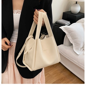 Detail of cream white lychee leather bucket bag with Fashion print and dual strap design