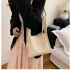 Close-up of beige lychee texture bucket bag with Fashion embossing and wide shoulder strap