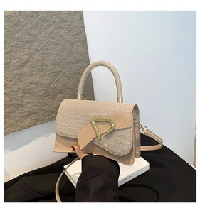 Close-up of apricot small square bag featuring glitter patchwork and gold D-shaped buckle