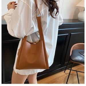 Detail of brown litchi pattern tote bag with embossed fashion text and long strap
