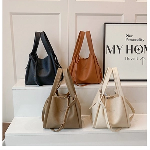 Detail of four colorful pebbled leather bucket bags showing wide handles and straps